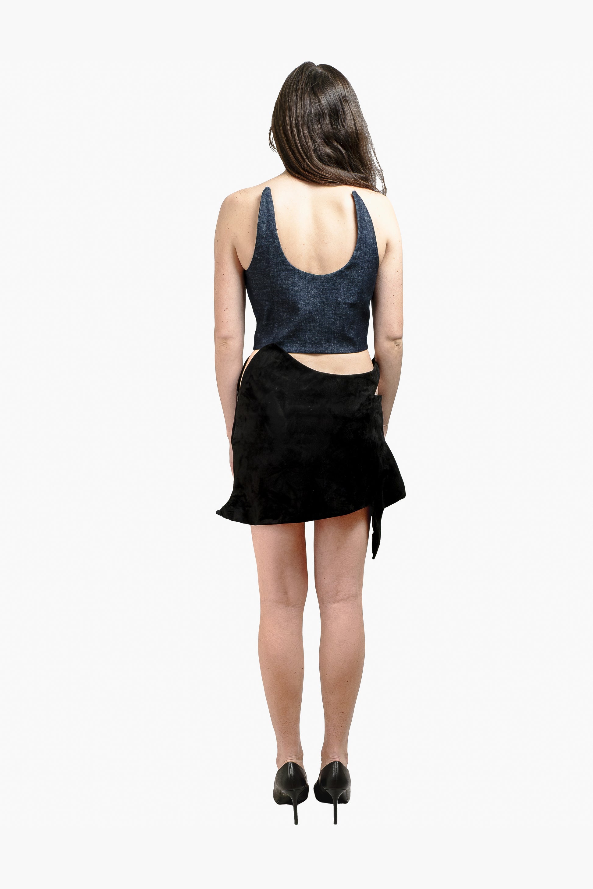 Back view of a black leather mini skirt and structured denim crop top